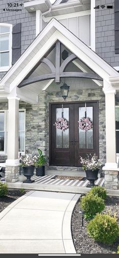 the front entrance to a house with flowers and wreaths on it's doors