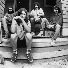 three men sitting on the steps with their skateboards in front of an old house