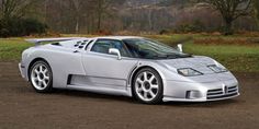 a silver sports car parked on top of a dirt road