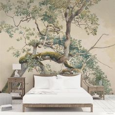 a bed sitting under a tree next to a painting on the wall in a bedroom