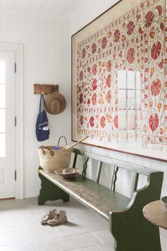 a wooden bench sitting in front of a painting on the wall next to a basket