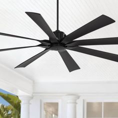 a ceiling fan with four black blades in a white living room, next to a large window