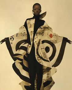 a woman in a black and white dress with musical notes on her coat over her shoulders