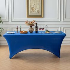 there is a blue table with food and drinks on it in front of a painting