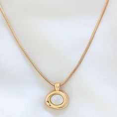 Elevate your everyday look with this gold-filled Molten Bezel Necklace, featuring a lustrous shell pearl at its center. The unique molten bezel design adds a modern, organic touch that makes this necklace stand out. Perfect for layering with other necklaces or wearing on its own for a minimalist statement. 14k Gold Filled Chain 24k Gold Filled Molten Bezel Charm: 21mm x 19mm Chain length: 16", 18", 20" Lobster clasp closure for secure wear Hypoallergenic, perfect for sensitive skin Water resista Modern Gold Pearl Necklace With Pendant, Modern Gold Pearl Necklace With Pearl Charm, Elegant Gold Shell Necklace With Pearl Charm, Elegant Shell Necklace With Round Pearl Pendant, Elegant Gold Shell Necklace With Clavicle Chain, Elegant Gold Shell Necklace With Pearl Drop, Elegant Gold Shell Necklace With Pearl Pendant, Elegant Gold Round Shell Necklace, Elegant Gold Shell Necklace With Round Pendant