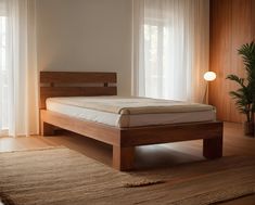 a bed sitting on top of a wooden floor next to a potted palm tree