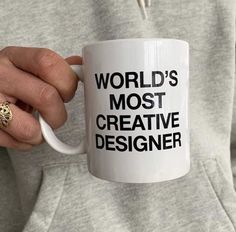 a person holding a coffee mug with the words world's most creative designer on it