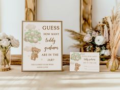 a baby shower sign next to a vase with flowers in it and two cards on the table