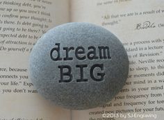 a rock with the words dream big on it sitting in front of an open book