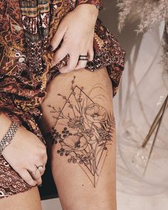 a woman's legs with tattoos on them and flowers in the middle of her thigh