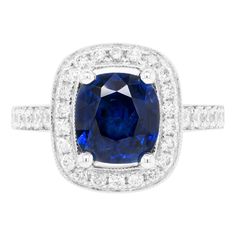 This lovely 18 carat white gold cluster ring is beautifully centred with a 2.52ct blue cushion cut sapphire, mounted in a four claw, open back setting. The vibrant stone is further highlighted by a halo of 22 round brilliant cut diamonds, all micro claw set around the beautiful sapphire. Finally, 30 round brilliant cut diamonds decorate the delicate shank and an open work gallery, making the total diamond weight 0.69ct. Stamped 750. UK finger size 'L’. Gia Certified Cushion Cut Sapphire Ring In Platinum, Gia Certified Cushion Cut Sapphire Ring In White Gold, Cushion Cut Sapphire Diamond Ring For Formal Occasions, Formal Sapphire Cushion Cut Diamond Ring, Sapphire Platinum Diamond Ring Cushion Cut, Sapphire Cushion Cut Diamond Ring In Platinum, Platinum Sapphire Cushion Cut Diamond Ring, Sapphire Diamond Ring With Cushion Brilliant Cut, Sapphire Diamond Ring With Cushion Cut