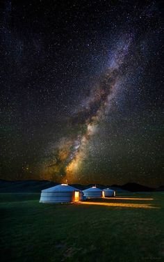 the milky shines brightly in the night sky above two yurts with lights on them