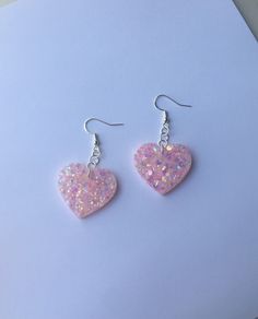 a pair of pink heart shaped earrings sitting on top of a piece of white paper