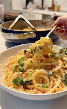 a person is holding a fork full of pasta