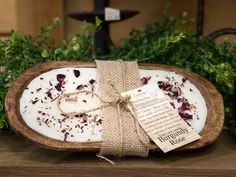 a wooden tray with a tag tied to it sitting on a table next to some plants