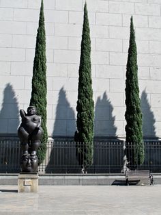 three tall trees are next to a statue in front of a building with an elephant on it