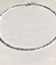 a beaded necklace with silver beads and glass beads on a white tablecloth background