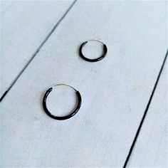 Black Hoop Earrings made by Silver Sterling 925. You can choose Size: - 10mm diameter x 1,2mm - 12mm diameter x 1,2mm - 14mm diameter x 1,2mm The black color is achieved by enameling silver with Ruthenium. In the seafaring tradition, the number of rings a sailor wore indicated the voyages he had completed. 1 hoop Cape Horn, 2 Cape of Good Hope, 3 Hoops around the world. Our earrings are sent in wooden boxes silk-screened by us, the boxes are made of recycled wood from the North of Galicia (Spain Black Minimalist Cartilage Earrings For Everyday, Black Minimalist Small Hoop Earrings, Minimalist Black Round Cartilage Earrings, Black Round Huggie Earrings For Everyday, Minimalist Black Small Hoop Huggie Earrings, Minimalist Black Hoop Cartilage Earrings, Minimalist Black Round Hoop Earrings, Small Black Hypoallergenic Hoop Earrings, Hypoallergenic Small Black Hoop Earrings