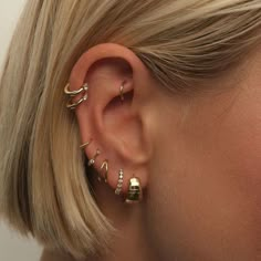 a woman wearing three different ear piercings on her left ear and the other one is gold