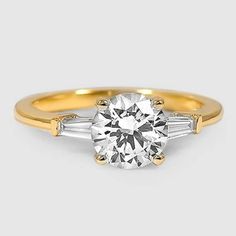 a diamond engagement ring with three baguets in yellow gold