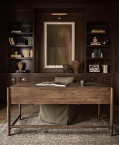 a wooden desk sitting on top of a rug in front of a book shelf filled with books