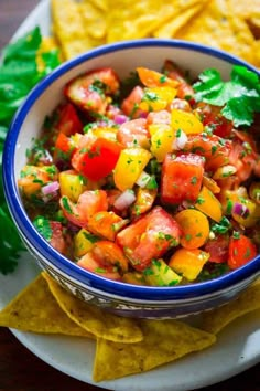 a bowl of salsa with tortilla chips and cilantro on the side