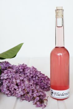 a bottle of pink wine next to some purple flowers