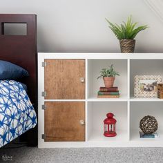 a white bookcase with wooden doors and drawers in a bedroom next to a bed