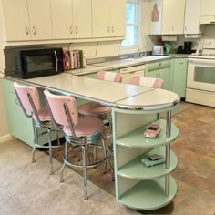 a kitchen with green cabinets and pink chairs