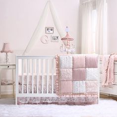 a pink and white baby's room with a crib, dressers, and bedding