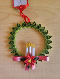 an origami wreath with candles and ribbon