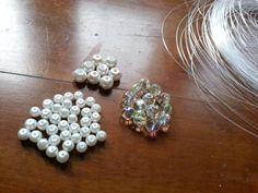 three different types of beads and feathers on a wooden table with one bead in the shape of a snowflake