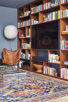 a living room with bookshelves and a television on top of the bookcase