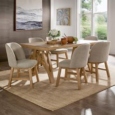 a dining room table with beige chairs around it