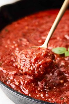 a wooden spoon scooping some meatballs out of a pot filled with marinara sauce