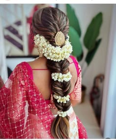 a woman with long hair and flowers in her hair is wearing a red sari