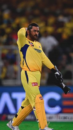 a man in yellow and blue uniform walking across a field with his hand up to the side