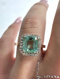 a woman's hand with an emerald and diamond ring