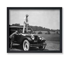 an old black and white photo of two men on top of a car