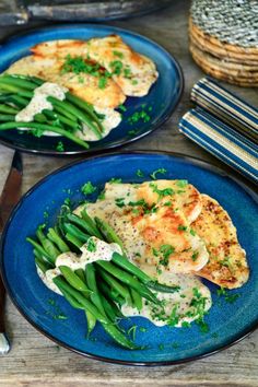 two blue plates topped with chicken and green beans