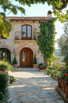 a stone house with potted plants on the front and walkway leading up to it