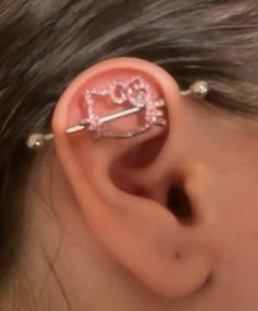 a girl with pink ear piercings that has the word love written on it and is wearing an ear pin