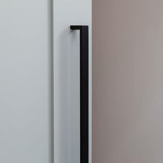 an open door with a black handle on the left side and a white wall in the background