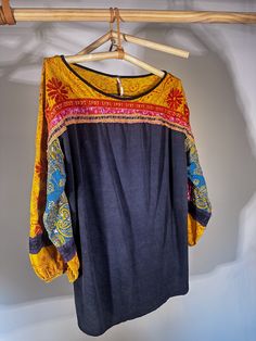 Free People patterned and embroidered long-sleeve shirt. The sleeves balloon or are slightly flared but gather at the three-quarter length close to the wrists. The base of the shirt is a soft navy blue cotton and the material of the shirt hangs loosely on the body in a flattering and casual fashion. This shirt can be styled up or down. Great for transition seasons. Casual Long Sleeve Embroidered Blouse, Long Sleeve Cotton Blouse With Embroidered Cuffs, Cotton Tops With Elastic Long Sleeves, Folk Style Long Sleeve Top With Embroidered Hem, Long Sleeve Blouse With Multicolor Embroidery, Long Sleeve Top With Multicolor Embroidery And Embroidered Hem, Black Long Sleeve Top With Embroidered Sleeves, Long Sleeve Cotton Embroidered Top With Cuffs, Embroidered Tunic Tops For Fall