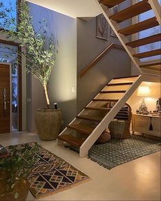 a living room filled with furniture and a stair case next to a potted plant