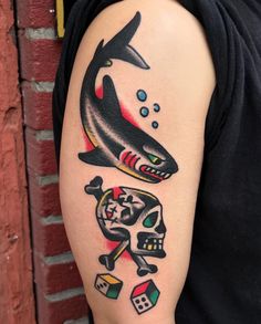 a man with a tattoo on his arm has a shark, dices and skull