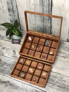 two wooden boxes filled with rocks on top of a white table next to a potted plant