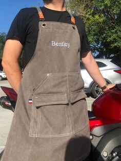 a man standing next to a motorcycle wearing an apron with the word bentley on it