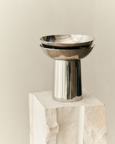 a silver bowl sitting on top of a white block