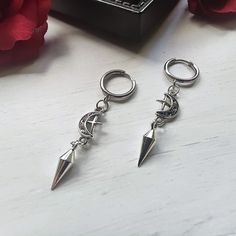 Beautiful gothic/punk spike huggie hoop earrings made of stainless steel with a detailed moon/star pendant. The earrings are hypoallergenic and do not tarnish. Outer diameter Huggie: approx. 6.3 inch Inner diameter Huggie: approx. 4.7 inch Length of spike pendant: approx. 0.6 inch Length of moon/star pendant: approx. 0.4 inch Total length: approx. 1.6 inch Huggie material: stainless steel Material spike: stainless steel Material moon/star pendant: silver-plated metal   Lead and nickel free I add Metal Huggie Cartilage Earrings, Gothic Silver Nickel-free Hoop Earrings, Gothic Silver Hoop Earrings Nickel Free, Silver Gothic Hoop Earrings Nickel Free, Adjustable Gothic Metal Cartilage Earrings, Silver Metal Emo Earrings, Silver Metal Emo Style Earrings, Emo Style Pierced Metal Earrings, Gothic Silver Metal Piercings